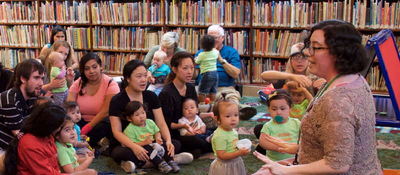 a librarian reads to group of babies and toddlers and their caregivers