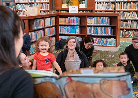 a librarian reads to a group of young kids and their caregivers