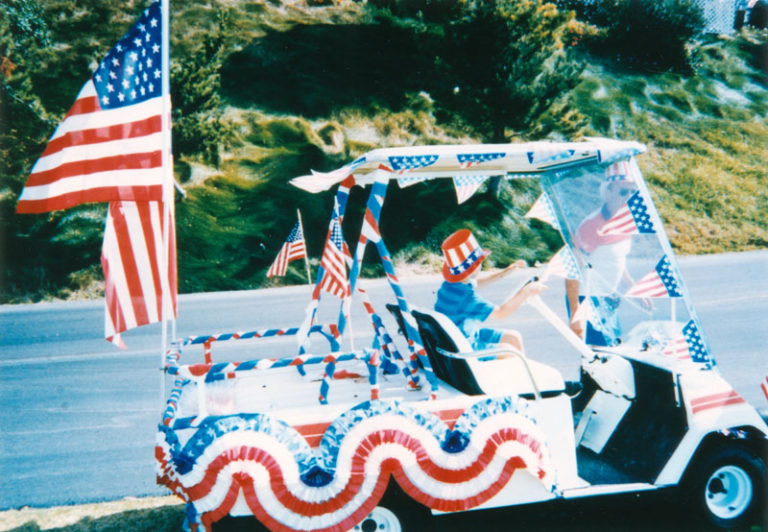 A boy drives a golf cart decorated for a Fourth of July parade in San Pedro.