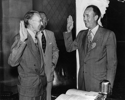 Los Angeles Police Chief William H. Parker raises his right hand (right) and takes his oath of office. The oath is administered by City Clerk Walter C. Peterson on August 9, 1950.