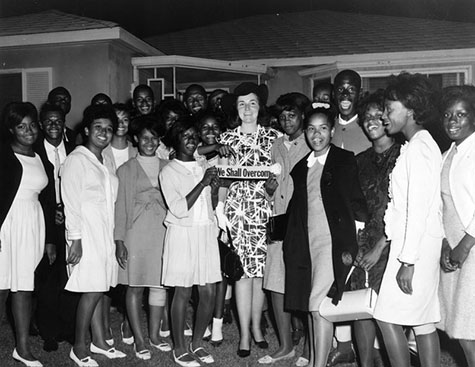 A youth group is involved in civil rights in 1965, holding a "We Shall Overcome" sign. 