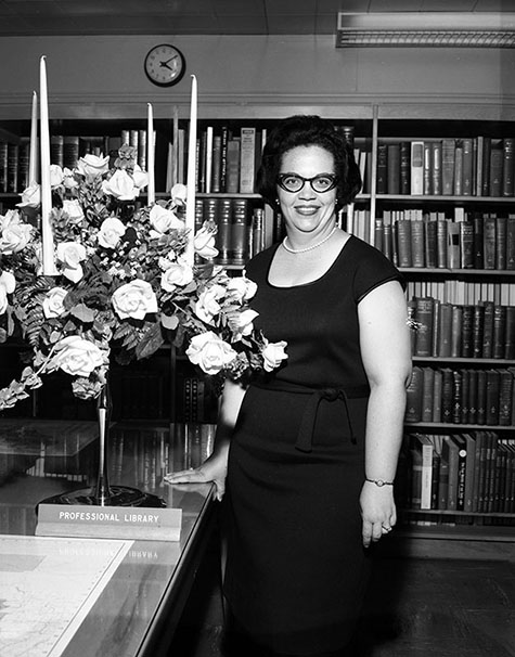 Portrait of Gloria Curtis, wife of Rolland Curtis, taken in a library