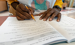 Man's hands holding pencil with open workbook