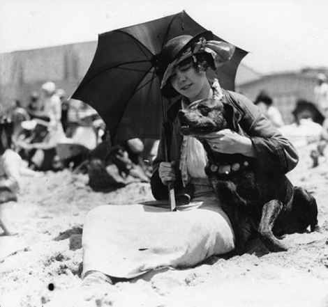 A young woman enjoys a sunny day on the beach with her dog