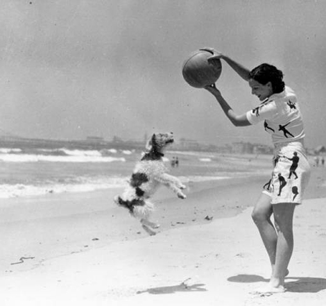 a woman plays ball with her dog. 1936