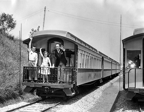 Walt Disney and two kids waving from a train