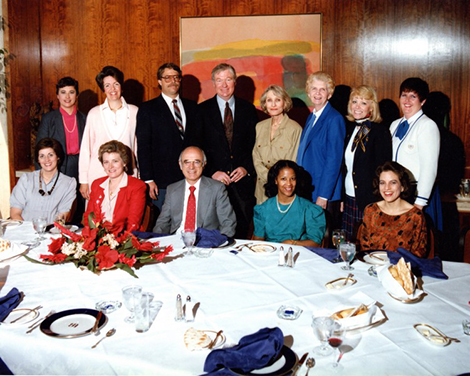 group of people in a wood-paneled room having dinner