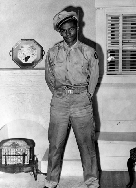 A young soldier poses in front of a fireplace. This photo was taken in 1943