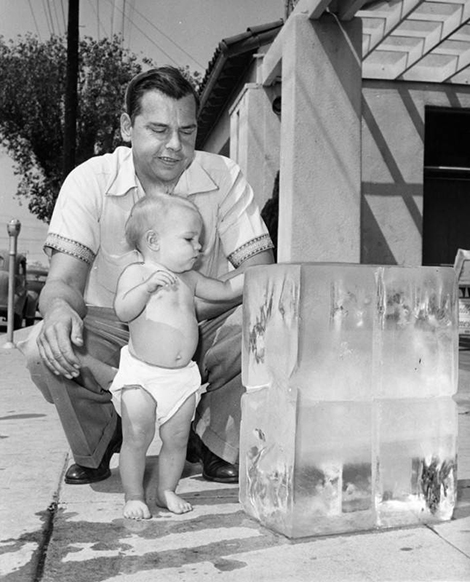 Baby touches block of ice on the sidewalk