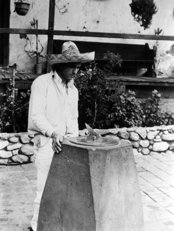 A man in Mexican dress looking at a sundial