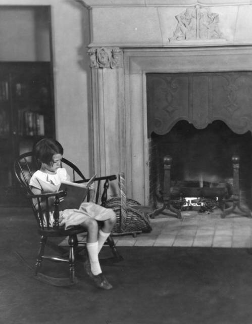 A young girl reading in front of the fireplace in the Children’s Room of the (1923) Hollywood Branch Library