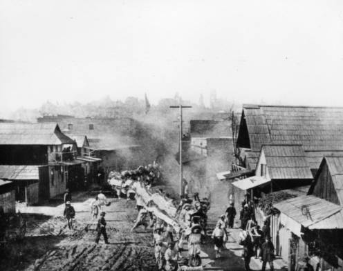 A Chinese dragon is paraded through the dirt streets of Old Chinatown