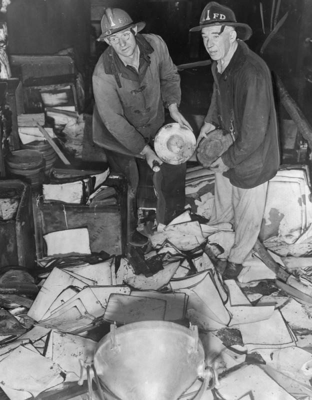 Firemen examine many reels of films and other property that were destroyed in a fire