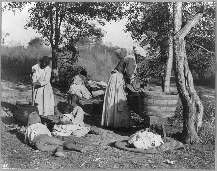 African American woman doing laundry with a scrub board and tub, c. 1900