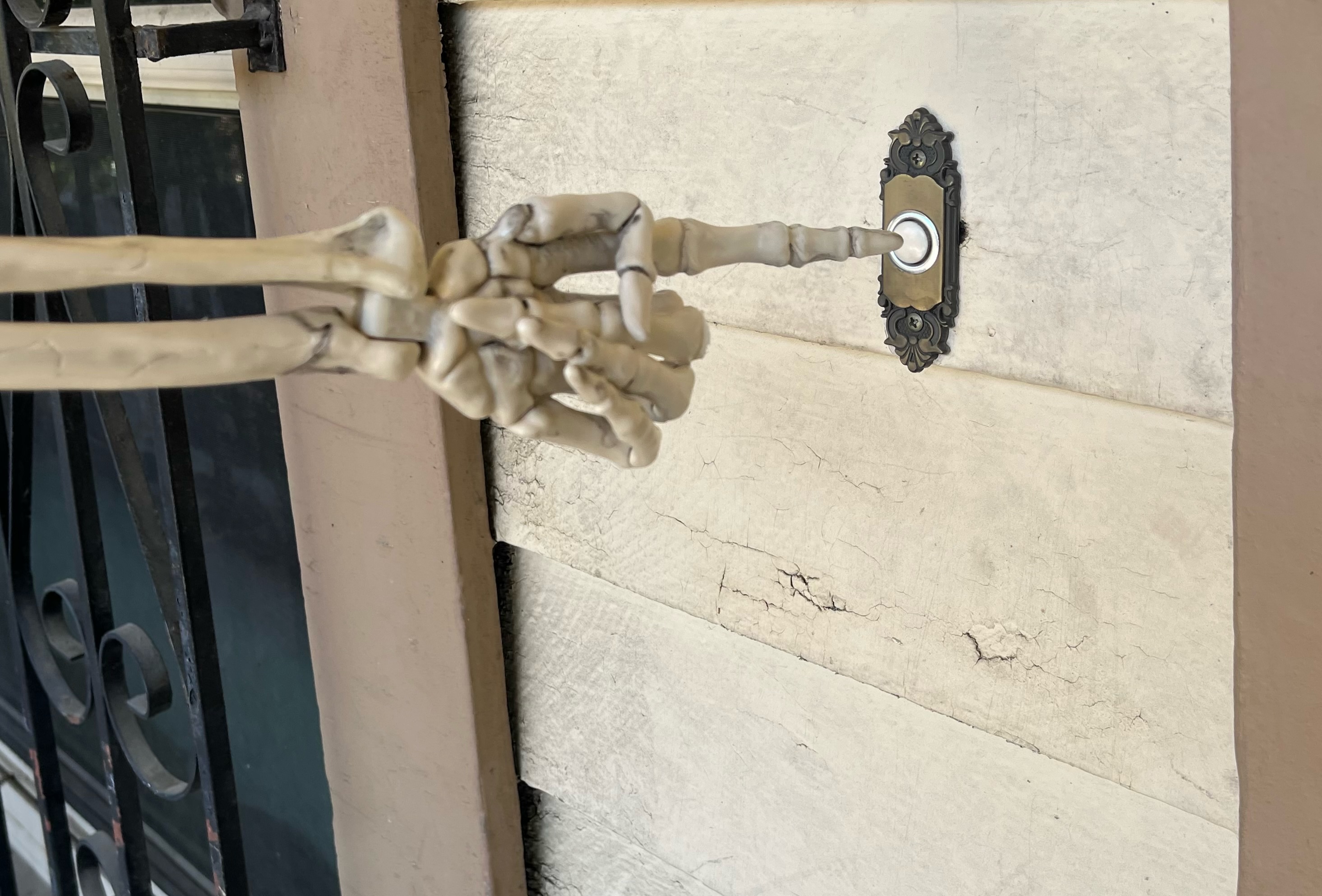 skeleton hand pushing a doorbell button