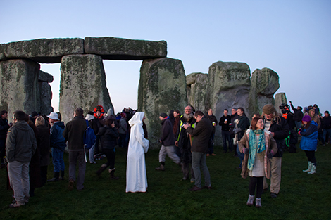 Stonehenge at dawn on the winter solstice. A large gathering of people are there to celebrate this event.