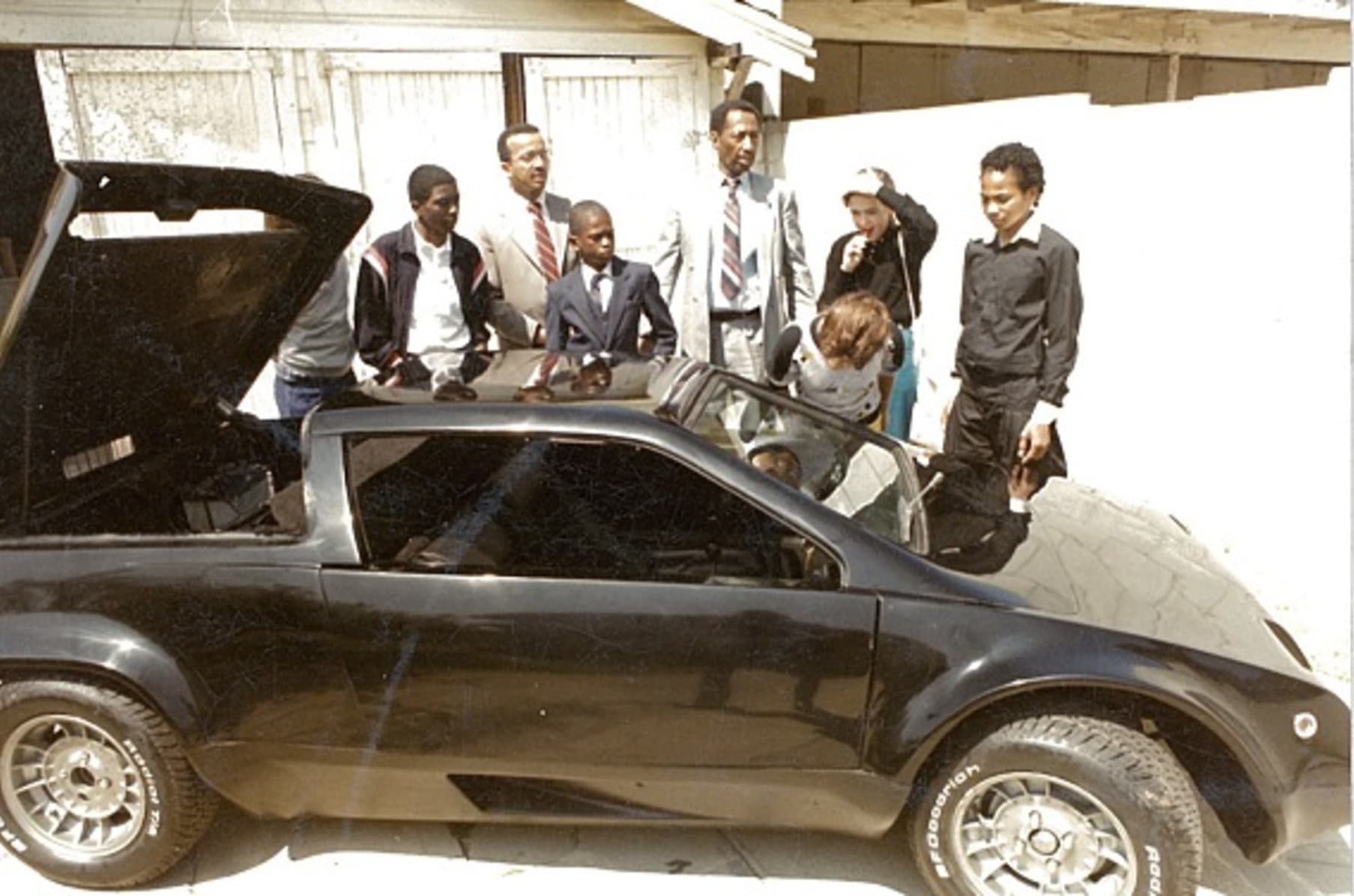 several people look at black car