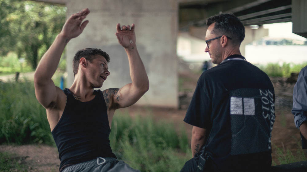 two men talking under a bridge