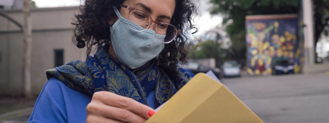a patron wearing a face covering holding a folder with a print order